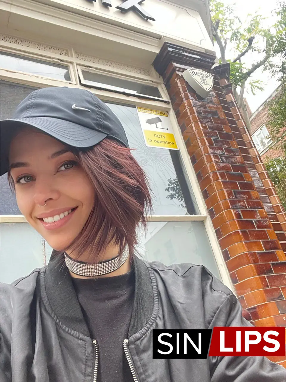 adjika taking a selfie wearing a black cap and black jacket outside