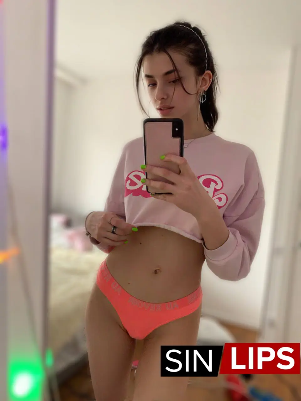 adjika wearing orange panties and pink top taking a selfie in the mirror